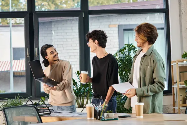 Три молодых человека, участвующих в оживленном обсуждении за ноутбуком в коворкинге, идеи стартапов — стоковое фото