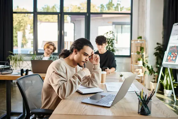 Thoughtful young entrepreneur analyzing data on laptop and near charts and notebook on table — Stock Photo