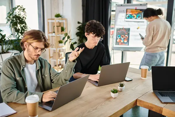 Jeune équipe de démarrage profondément concentré tout en travaillant sur les ordinateurs portables dans un espace de coworking, les hommes dans la vingtaine — Photo de stock