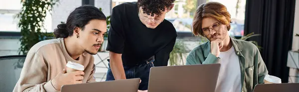 Young men in 20s analyzing project together on laptops in a sunlit coworking space, startup banner — Stock Photo