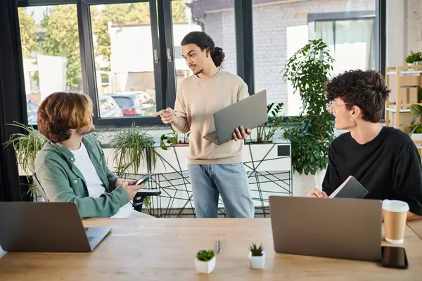 Team lead discussing project details with attentive colleagues in a workspace, men in their 20s — Stock Photo