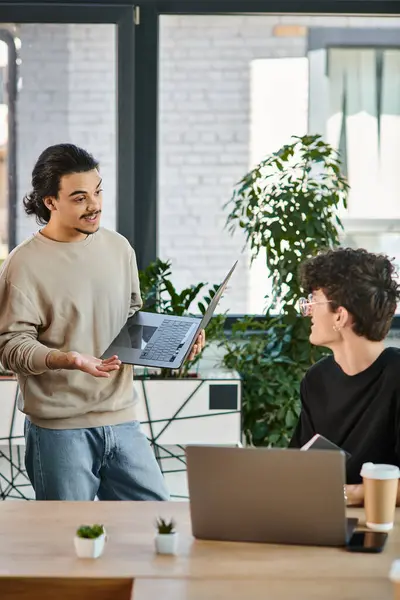 Team lead discussing project details with attentive colleague in a workspace, men in their 20s — Stock Photo