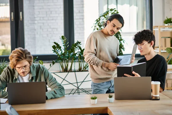 Team lead discussing project details with concentrated colleagues in a workspace, men in their 20s — Stock Photo