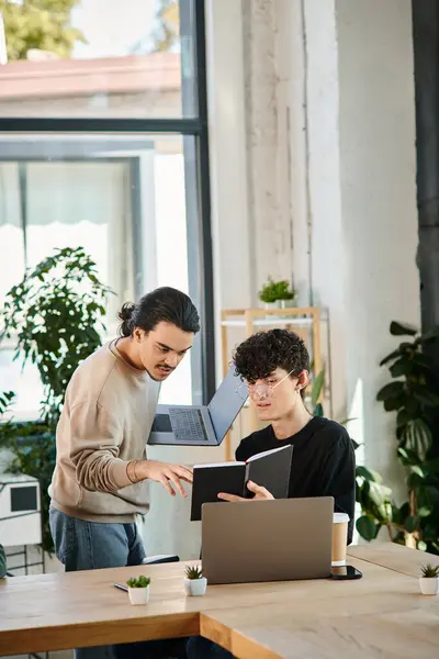 Team lead discussing project ideas with curly colleague in a workspace, men in their 20s — Stock Photo