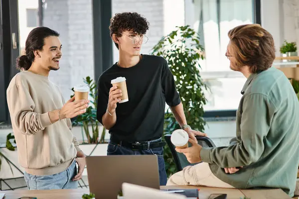 Freundliches Gespräch zwischen drei jungen Mitarbeitern mit Coffee to go im modernen Büro, Start-up — Stockfoto