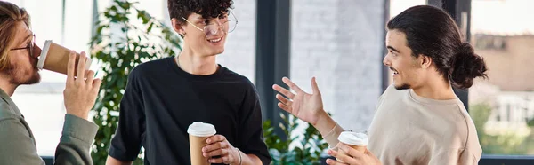 Conversa amigável entre três jovens colegas de trabalho segurando café para ir no escritório moderno, banner — Fotografia de Stock