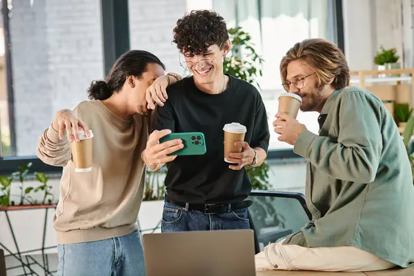 Hombres de negocios alegres disfrutando de una pausa para tomar un café y una selfie en un espacio de coworking, hombres de 20 años - foto de stock
