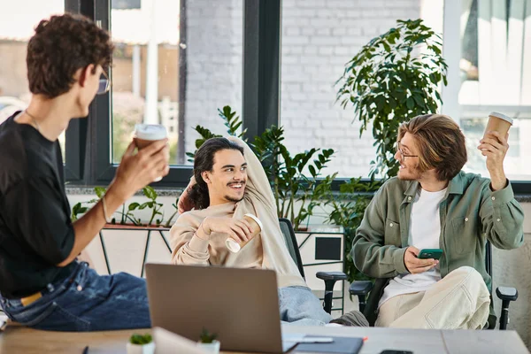 Cheerful young men in their 20s chatting during coffee break at the office, startup team members — Stock Photo