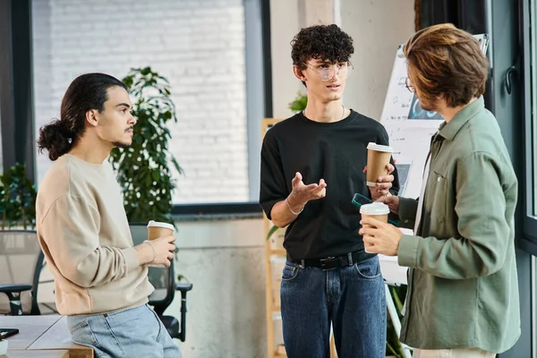 Jóvenes compañeros de trabajo en sus años 20 compartiendo ideas sobre el café en el entorno moderno de la oficina, equipo de startup - foto de stock