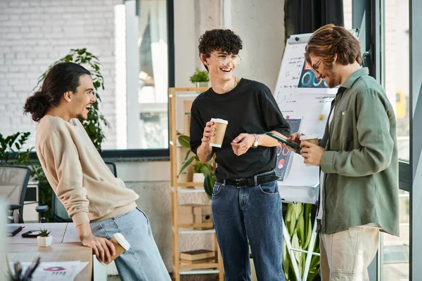 Jeunes collègues dans la vingtaine partageant des idées et riant autour d'un café dans un bureau moderne, équipe de démarrage — Photo de stock