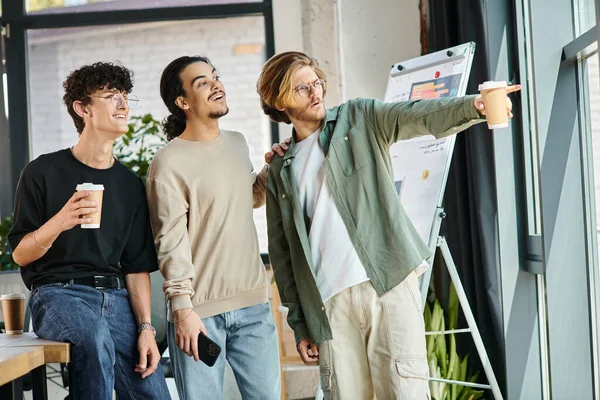 Young man in 20s showing something to startup team members and  looking away in a bright future — Stock Photo