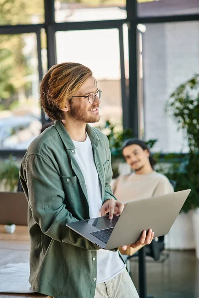 Positives junges Startup-Team-Mitglied in Brille mit Laptop und in einem modernen Coworking Space — Stockfoto