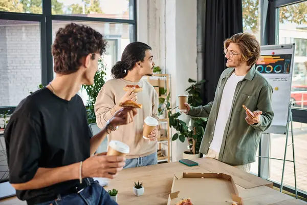 Hombres alegres comiendo pizza y charlando en un ambiente agradable y relajado, equipo durante la pausa para el almuerzo - foto de stock