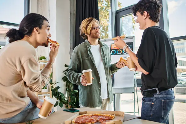 Young men eating pizza and chatting in friendly and relaxed atmosphere, team during lunch break — Stock Photo