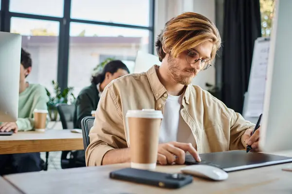 Focused man working on creative project and using his tablet in startup coworking, retouching team — Stock Photo