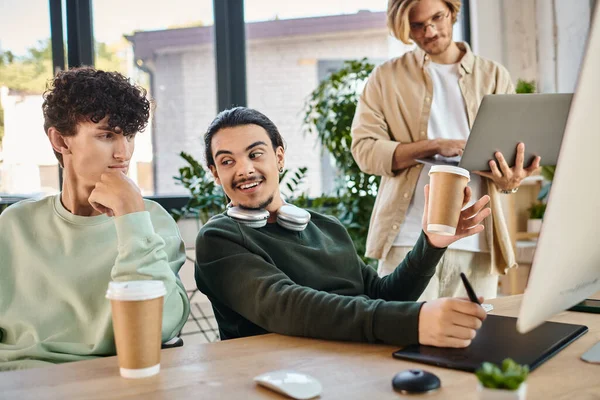 Happy post production team of young men focused on a retouching project in a well-lit office — Stock Photo