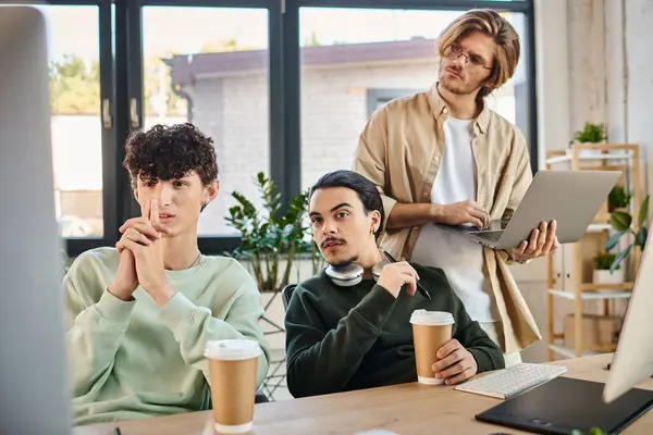 Post production team of young men focused on a retouching project on monitor in a well-lit office — Stock Photo