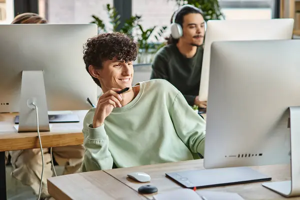 Felice uomo riccio impegnato nel lavoro di ritocco con penna stilo in mano guardando il monitor — Foto stock