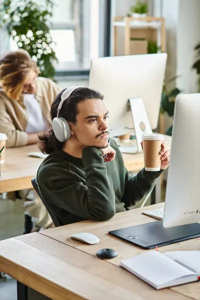 Pensoso maschio professionista in cuffie che tengono il caffè per andare a guardare il monitor in ufficio — Foto stock