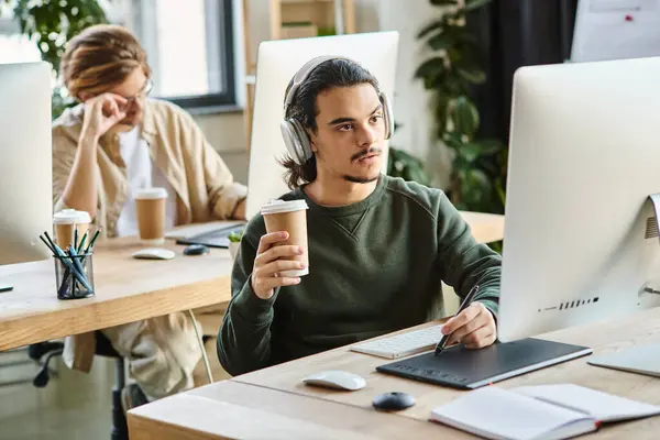 Пенсійний чоловік-професіонал в навушниках, що тримає каву, щоб піти і використовувати графічний планшет в офісі — стокове фото
