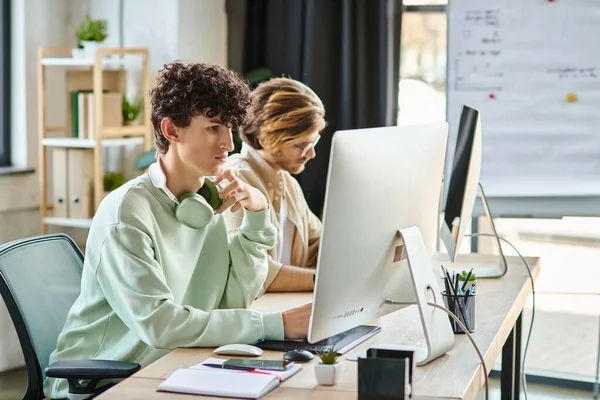 Uomo dai capelli ricci concentrandosi sul ritocco del lavoro vicino al collega in uno spazio ufficio startup — Foto stock