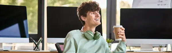 Happy young man with headphones sitting in office chair and holding coffee, post production banner — Stock Photo