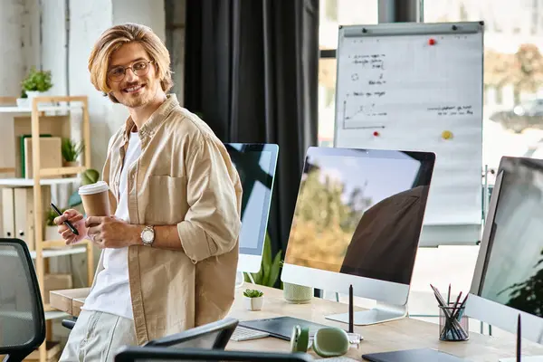 Happy man in glasses holding coffee and stylus pen in modern office setup, post production — Stock Photo