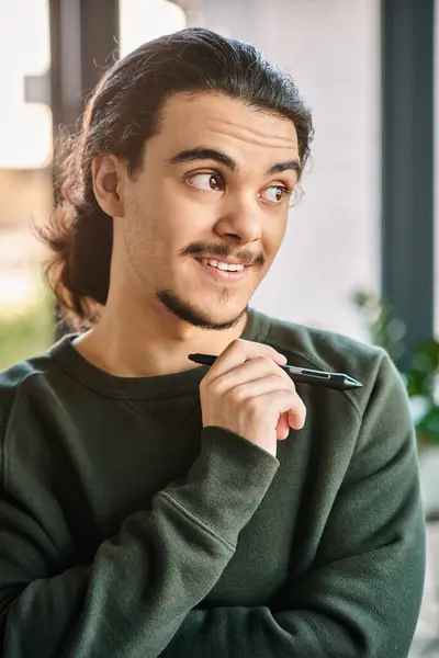 Junge Berufstätige stehen mit Stift und lächeln im Postproduktionsraum, Mann in den 20er Jahren — Stockfoto