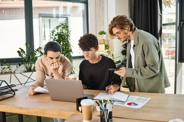 Drei Teammitglieder in Projektdiskussion im Startup-Büro, Männer in den Zwanzigern beim Blick auf Laptop — Stockfoto