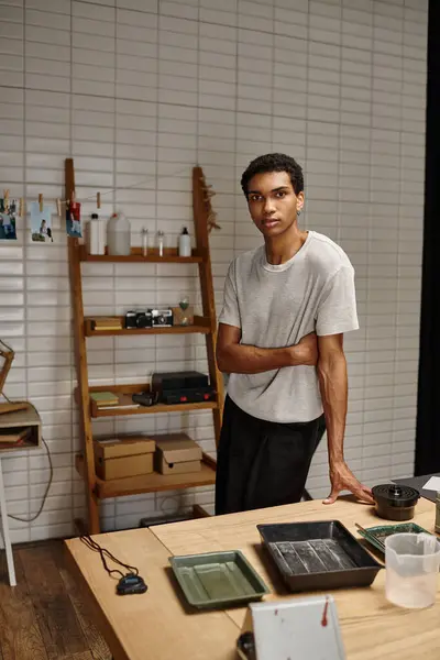Jeune photographe afro-américain debout dans un laboratoire photo avec des photos de films suspendus — Photo de stock