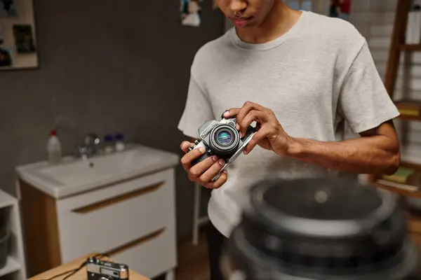 Vista recortada de un joven fotógrafo afroamericano manejando expertamente una cámara vintage en un laboratorio de fotografía - foto de stock