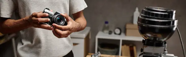 Hombre negro recortado Sujetando intencionadamente una cámara analógica mientras está de pie en un laboratorio de fotos, pancarta - foto de stock