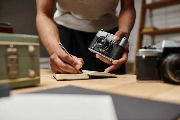Abgeschnittener afrikanisch-amerikanischer Kerl im Schreiben vertieft, seine analoge Kamera im Fotostudio haltend — Stockfoto