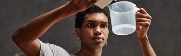 Homem afro-americano bonito derramando solução química em copo de medição, bandeira do desenvolvimento do filme — Fotografia de Stock