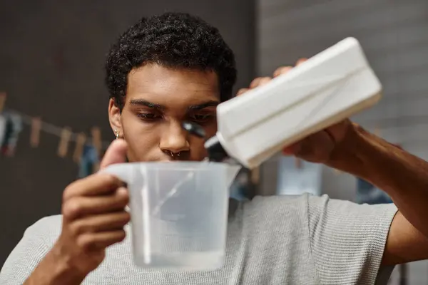 Bonito fotógrafo afro-americano derramando solução química em copo de medição, desenvolvimento de filme — Fotografia de Stock