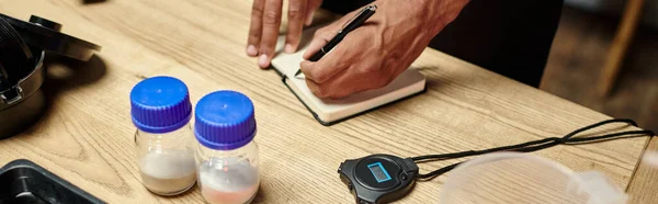 Cropped view of african american man taking notes near bottles with film developing powder, banner — Stock Photo