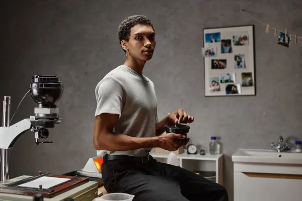 Dreamy young african american man securing a film canister lid in darkroom, traditional photography — Stock Photo