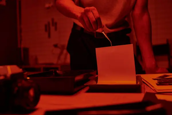 Cropped view of photographer immerses photo paper in a darkroom bath with chemicals — Stock Photo