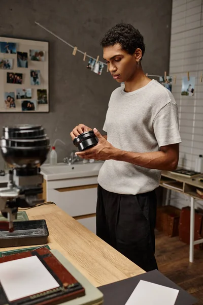 Fotografo afroamericano esamina sviluppatore di film in camera oscura, circondato da apparecchiature analogiche — Foto stock