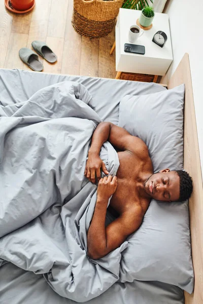 Top view of young and muscular african american man sleeping on comfortable bed at home in morning — Stock Photo
