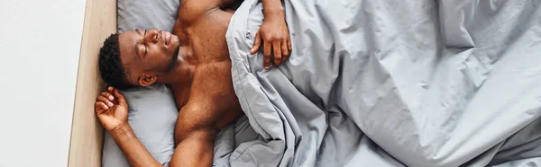 Blick von oben auf junge muskulöse afrikanisch-amerikanische Mann schlafend auf bequemen Bett in der Früh, Banner — Stockfoto