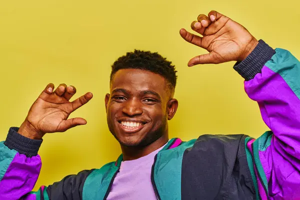 Excited african american man in trendy casual clothes gesturing and looking at camera on yellow — Stock Photo