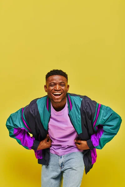 Excited african american man in fashionable casual attire laughing at camera on yellow backdrop — Stock Photo