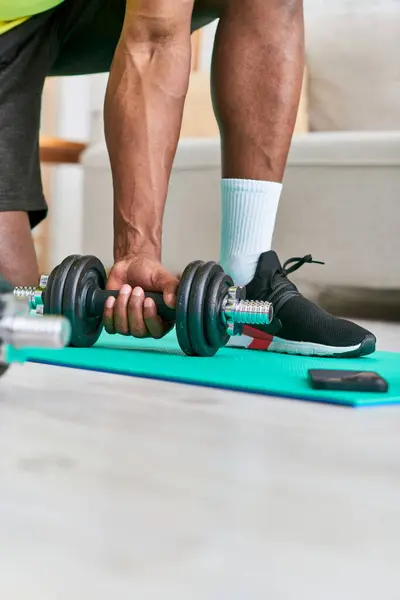 Partial view of fit african american man in sportswear training with dumbbell in living room at home — Stock Photo