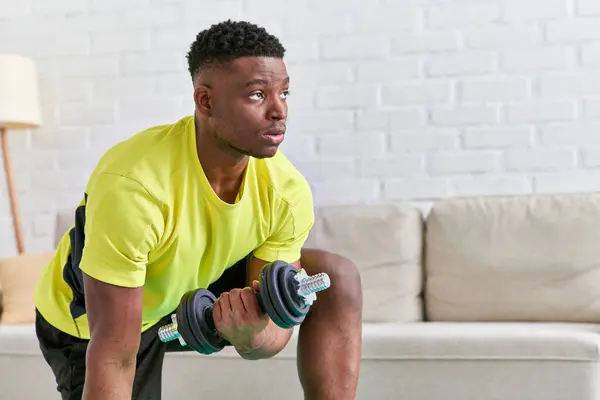 Confiante homem afro-americano em sportswear trabalhar com halteres no tapete de fitness em casa — Fotografia de Stock