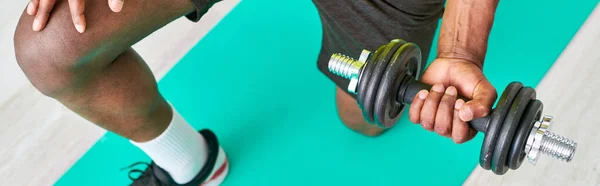 Vue partielle de l'homme afro-américain dans l'entraînement de vêtements de sport avec haltère sur tapis de fitness, bannière — Photo de stock