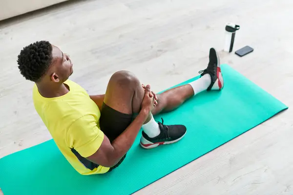 Hochwinkel-Ansicht der fit afrikanisch-amerikanischen Matte sitzen und dehnen auf Fitness-Mann im Wohnzimmer — Stockfoto