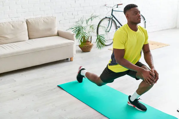Schöner afrikanisch-amerikanischer Mann in Sportbekleidung dehnt sich auf Fitnessmatte im Wohnzimmer zu Hause — Stockfoto