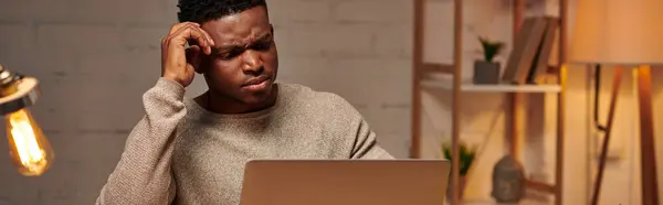 Grave pigiste afro-américain travaillant à l'ordinateur portable dans le bureau à domicile la nuit, bannière horizontale — Photo de stock