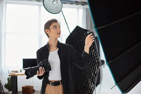 Beautiful young female photographer in everyday clothes posing in her studio and looking away — Stock Photo